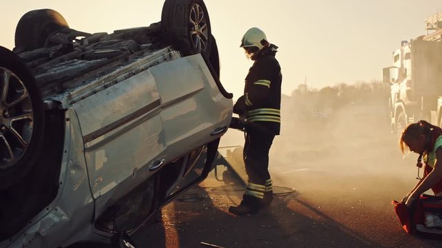 On the Car Crash Traffic Accident: Paramedics and Firefighters Rescue Injured Trapped Victims. Medics give First Aid to Female on Stretchers. Firemen Use Hydraulic Cutters Spreader to Open Vehicle