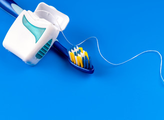 Toothbrush and floss on blue background.- Image