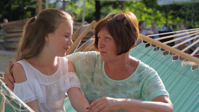 Intimate talk heart-to-heart between grandmother and granddaughter teenager girl telling her secrets and mature womat gives an advice