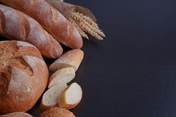 Bakery - gold rustic crusty loaves of bread and buns on black chalkboard background.
