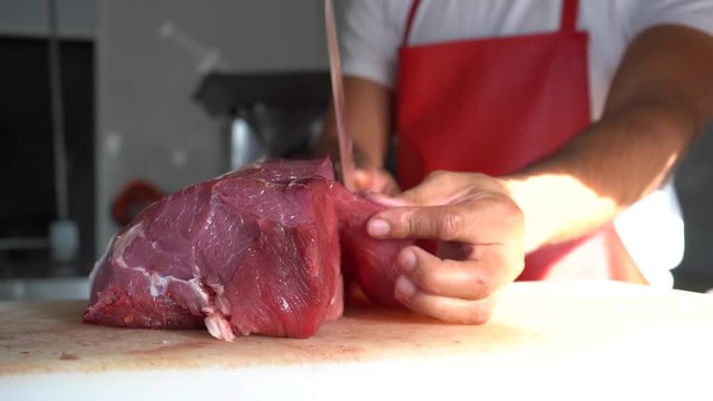 El carnicero está cortando la carne con un cuchillo muy afilado.