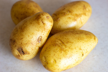 Studio macro of stacked potatoes with soft shadows on a white surface. Copy space. Golden brown potatoes on white surface. Golden round potatoes on a white surface