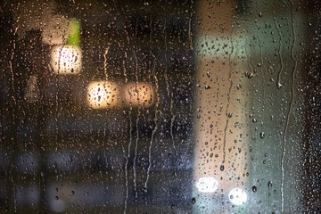 Rain drops. Rain drops on glass on a dark background. Rain drops on the window on a dark background. Water drop on window on a dark background