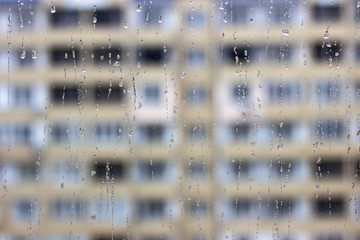 Close up shot of rain drops on glass window against sunset. Raindrops on window against a light background. Raindrops on the window