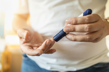 Obraz na płótnie Canvas Close up of man hands using lancet on finger to check blood sugar level by Glucose meter. Use as Medicine, diabetes, glycemia, health care and people concept.