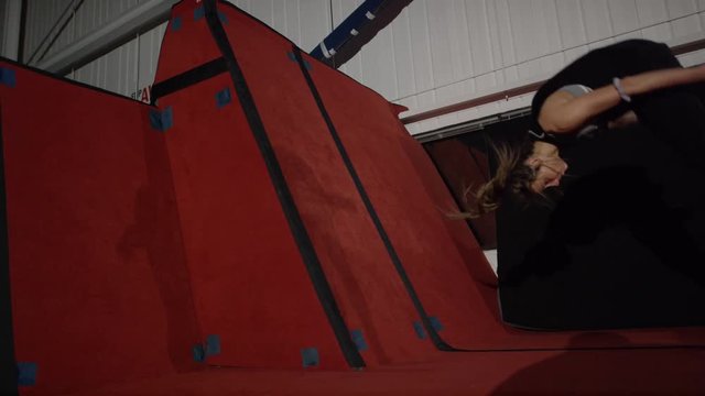 Female athlete doing impressive tumbling on trampolines and gym parcour equipment