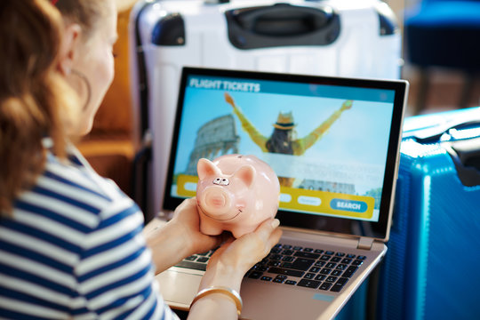 stylish woman booking tickets and holding piggybank