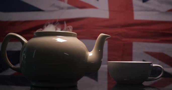 Against the background of the English flag brewed tea with English tea and poured into a mug from where there is a lot of smoke. Concept of: British Tea, Slow Motion, Flag, Real Tea.