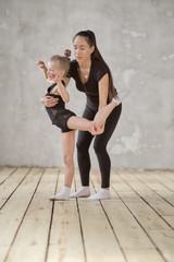 happy woman and little girl study in classroom. teacher and teacher in the dance class. individual sessions. teacher carefully helps to stretch the muscles