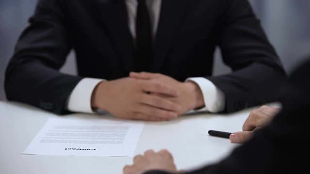 Businessman signing contract and shaking partners hand, cooperation close-up