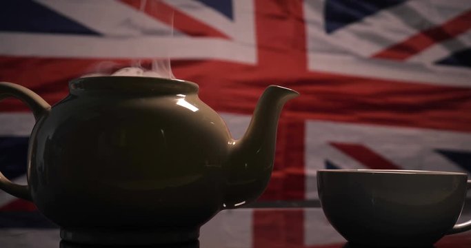 Against the background of the English flag brewed tea with English tea and poured into a mug from where there is a lot of smoke. Concept of: British Tea, Slow Motion, Flag, Real Tea.