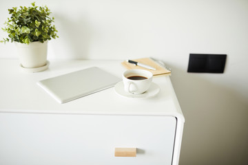 Group of stationary objects on white nightstand or chest of drawers in the room