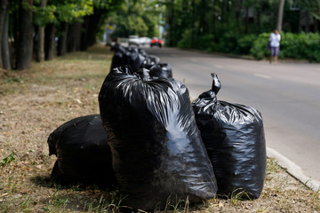 large black trash bags filled with garbage are on the road. Clean area concept.