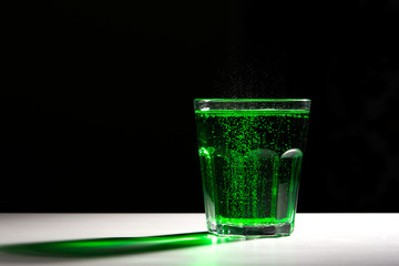glass with green soda on a dark background