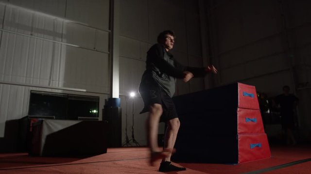 Man training in parcour in the gym with padded equipment and obstacles