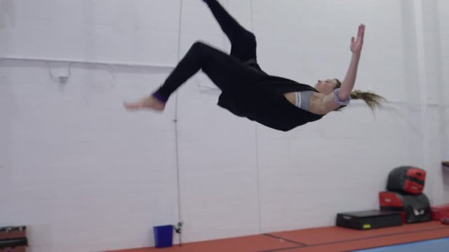 Female athlete doing impressive tumbling on trampolines and gym parcour equipment