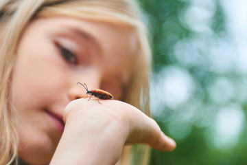 Child girl examining a beetle on her hand - Powered by Adobe