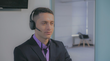 Portrait handsome man talking on helpline answer phone call using headset. Smiling friendly worker talking with customer. Close up employee working in support.