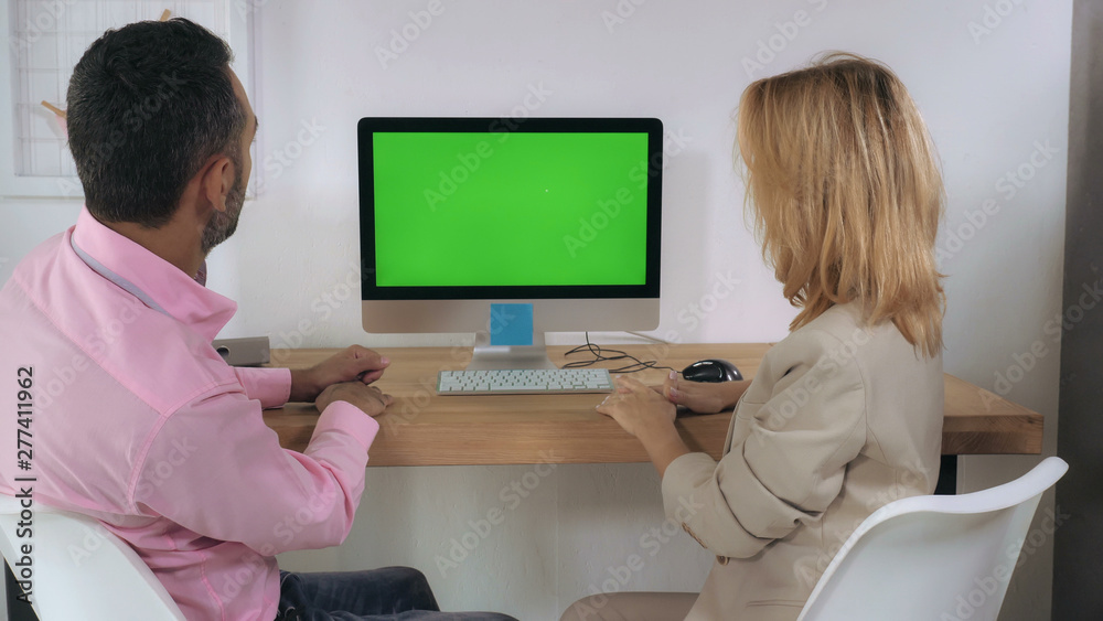 Poster business people sitting in front of computer with green display talking and looking on screen pc. ad