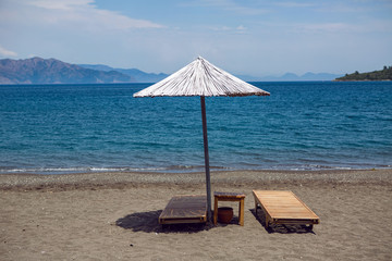 sunbed with umbrella on gray sand on an empty beach