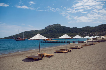 sunbed with umbrella on gray sand on an empty beach