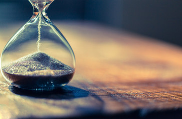 Sand running through the bulbs of an hourglass measuring the passing time in a countdown to a deadline with copy space. - obrazy, fototapety, plakaty