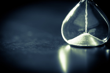Sand running through the bulbs of an hourglass measuring the passing time in a countdown to a deadline with copy space.