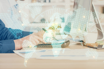 Fototapeta premium Double exposure of businessman working on laptop on background. International business hologram in front. Concept of success.