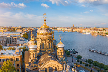 Fototapeta na wymiar Aerial view of the domes of the Assumption Church on the embankment of the Neva River, in the distance Isaaic Cathedral.