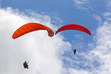 Red paragliders in a blue sky