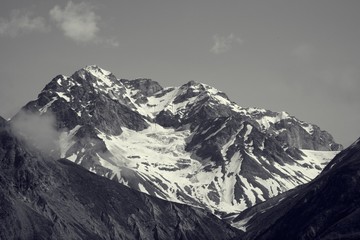 Closeup on snowy mountain peak half in sunlight and half in shadow