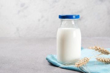 Bottle of milk with blue towel and wheat ears on a table