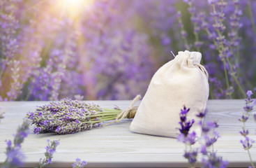 Essential lavender bouquet and sachet on wooden board. Horizontal close-up.