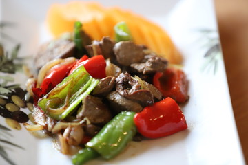 Fried chicken liver with sauce and vegetables and persimmon .
