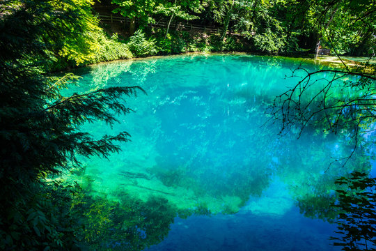 Germany, Blue glassy waters of source blue pot (blautopf) in blaubeuren, a natural monument inside green forest of swabian jura landscape near ulm