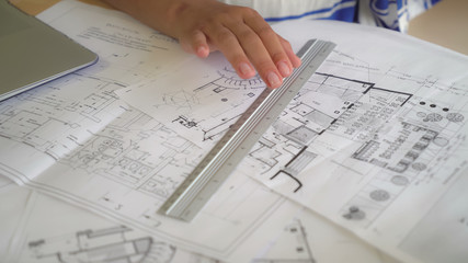 Close up desk with paper documents plan building. Woman draws details with pencil