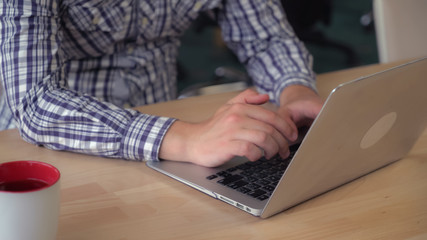Male hands typing on laptop. Close up details guy wearing in casual shirts entering data on...