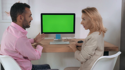 People in the office. Man showing presentation using green screen on computer. Mixed race manager telling about new products caucasian businesswoman listening and looking on display - Powered by Adobe