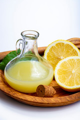 Fresh lemon juice made from ripe yellow Sicilian lemons used for cooking in glass bottle on olive wood plate