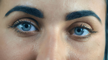 Close up woman wonderful blue eyes, black eyebrows and eyelashes