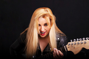 Beautiful blonde girl in rock style on a black background.