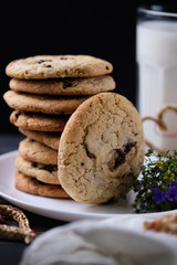 American chocolate cookies, a glass of milk. Surprise for Valentine's Day. Dark wooden table, black background and linen.