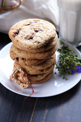 American chocolate cookies, a glass of milk. Surprise for Valentine's Day. Dark wooden table, black background and linen.