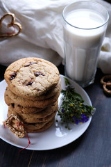 American chocolate cookies, a glass of milk. Surprise for Valentine's Day. Dark wooden table, black background and linen.