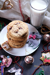 American chocolate cookies, a glass of milk and Christmas decorations. Dark wooden table and pink background. Cookies for the New Year.