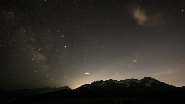 Star time lapse of the Milky Way in the sky over Wasatch mountain range as clouds fade away in Utah over Timpanogos.