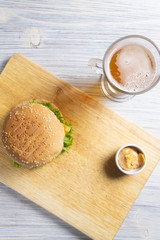 Burger with beef patty, salad, a slice of tomato and cheese, onions and sauce with paprika in a grilled bun with sesame