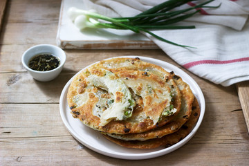 Homemade appetizing scallion pancakes and a bunch of green onions. Rustic style.
