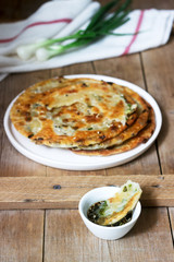 Homemade appetizing scallion pancakes and a bunch of green onions. Rustic style.