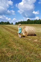 girl in a field with bales of hay